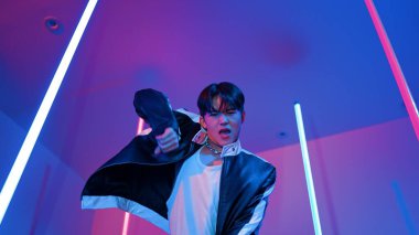 Profesyonel sokak dansçısının sıradan kıyafetlerle kameraya baktığı alçak açılı kamera. Stüdyoda mor ışık altında dururken şehirde pop müzik yapan yetenekli bir sanatçı. Kapatın. Mutluluk.