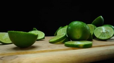 Yakın plan, canlı bir dilim taze kireç kırsal bir ahşap kesme tahtasının üzerinde duruyor. Tazelik ve canlılık yayıyor. Kesme tahtasına konmuş yeşil limon diliminin yarı saydam zarları. Geliştirilebilir.