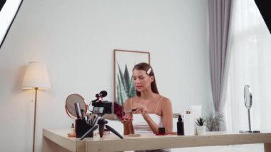 Sosyal medya için güzellik ve kozmetik video içeriği hazırlayan genç bir kadın. Güzellik blogcusu kameraya gülümserken seyircilere ve takipçilere güzellik bakımını gösteriyor. Düzenle