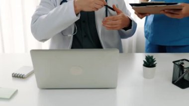 Hastane masasında birlikte çalışan ve tıbbi tedavi planlayan çeşitli profesyonel sağlık görevlileri. Takım çalışması başarılı hastalıklara ve hastalıklara yol açar. Ağır çekim. Katı.