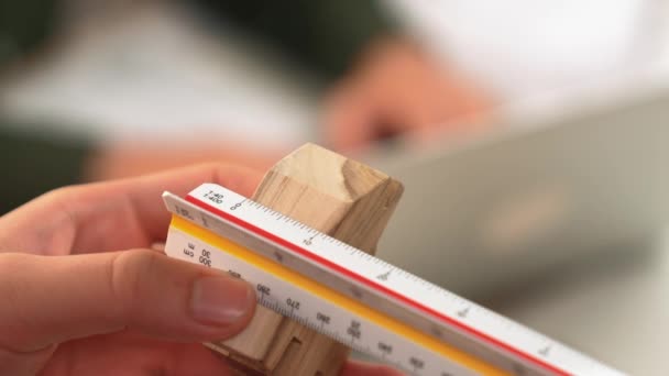 一个熟练的建筑师或安全工程师的视频使用刻度尺 测量工具 测量家庭形状的木块来设计工作室桌上的房屋建造 — 图库视频影像