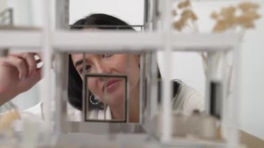 Ev modeli yapısını kendinden emin bir şekilde kontrol etmeye odaklanan genç, güzel, beyaz, yetenekli mimar mühendisinin yakın çekimi. Yaratıcı ve profesyonel tasarım konsepti. Portre. Tertemiz..