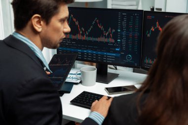 Dinamik borsada döviz kuru yatırımını tartışan iki ticaret simsarı iki bilgisayar ekranında gerçek zamanlı risk grafiği ya da modern ofisteki kar noktasını karşılaştırıyor. Varsayım.