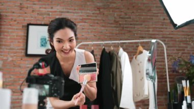 Kadın nüfuzlu kişi canlı yayın yapan video görüntülerini sosyal medya ya da blog üzerinden gözden geçiriyor. Kozmetik stüdyosu ışıklandırmalı mutlu genç kız çevrimiçi pazarlama oturumu yayını için..