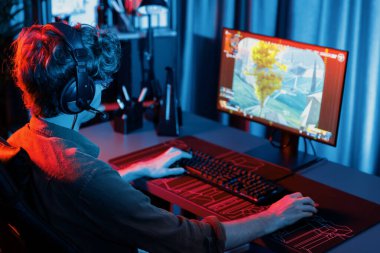 Genç oyun flamasının sunucu kanalı, takım oyuncusu, dijital neon odasında mikrofonlu kulaklık takarak bilgisayar ekranında çoklu oyuncuyla savaş oyunu oynuyor. Toplayıcı.