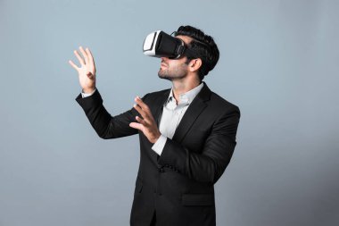 İş adamı VR gözlüğü kullanarak veri analizi yapıyor. Proje yöneticisi beyaz arka planda takım giyerken metaverse ya da sanal gerçeklik dünyasına girerek iş stratejisini kontrol ediyor. Sapma.