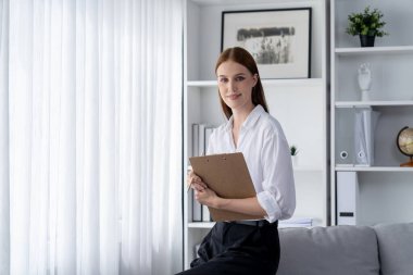 Klinikteki psikolog kadın. Profesyonel portresi. Dostane gülümsemesiyle hastayı psikoloğa davet ediyor. Tecrübeli ve kendine güvenen psikolog son derece uzmandır.