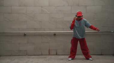 Yakışıklı koreograf gri arka planda sokak dansı yapıyor. Genç çekici erkek dansçı şık kıyafetler giyerken gösteri yapıyor. Hareketli bir adım. Uzayı kopyala Açık hava sporu 2024. Yumuşak bir şekilde..