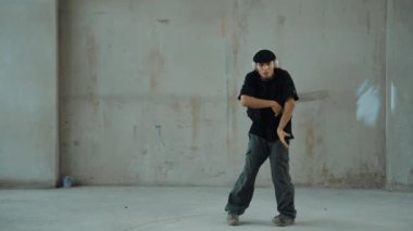 Kulaklıktan çimento arka planda müzik dinlerken break dans pratiği yapan yakışıklı bir hippi. Sokak dansçısının hareketli çekimi robot dansı yapar. Açık hava sporu 2024. Modern dans. hiphop.
