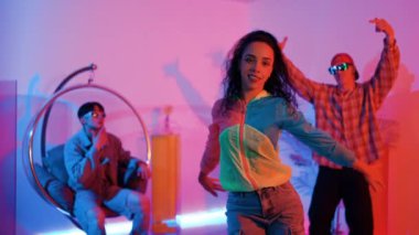 İspanyol hipster renkli kıyafetler giyer ve serbest stil müziğe el sallar. Profesyonel break dansçı neon ışıklarıyla ve modern stüdyo arkadaşlarıyla coşkuyla dans ediyor. Mutluluk.