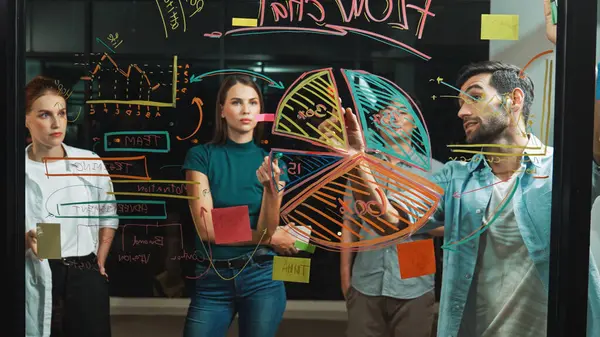 Yetenekli erkek lider, istatistik grafiğini uzman yatırımcılara açıklıyor. Akıllı iş adamı sunar, finans planlarını gece ofisindeki cam duvardaki yatırımcılara gösterir. İş konsepti. İzleme