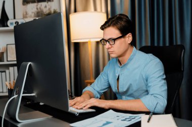 Akıllı iş adamı iş paragrafı dinamik pazarlama analizi planını analiz ediyor. Kağıt kağıtları ve bilgisayar monitörü raporlarını gece evdeki belge verileriyle karşılaştırmak için hazırlıyor. Bireysel.