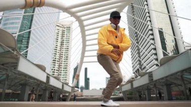 Asyalı hippi break dans çalışmasının düşük açılı kamerası ya da kulaklık takarken break dans performansı. Serbest dans, break dans, sokak dansı. Neşeli bir ruh hali. Açık hava sporu 2024. Yumuşak bir şekilde..