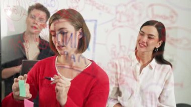 Profesyonel iş adamları pazarlama projesi için beyin fırtınası yapıyor ve birlikte çalışıyorlar. Kafkasyalı kadın lider fikrini nota yazarken iş arkadaşı da fikrini kendine güvenerek sunuyor. Tertemiz..