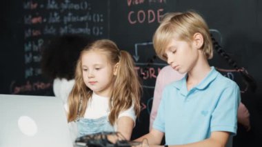 Akıllı kız, çeşitli arkadaşlarıyla dizüstü bilgisayar programlama kodları kullanıyor. Mikroçip ve ana pano dağılımı olan masa, BTMM sınıfında, karatahta, kodlama kombinasyonuyla yazılmış. Etkinlik.