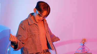 Asyalı sokak dansçısının neon ışıkla pop müziğe geçişine yakın çekim yaparken çeşitli arkadaşlar oturuyor ve performansı destekliyor. Profesyonel sanatçı stüdyoda dans figürleri yapıyor. Mutluluk.