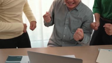 Yavaş çekim heyecanlı ve mutlu yaratıcı iş adamları grubu toplantı masasında başarılarını kutluyor. Etrafta dokümanlar ve dizüstü bilgisayarlar var. Yaratıcı iş başarısı kavramı. Değiştirilmiş
