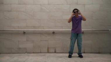 Yakışıklı hippi dans ederken müzik dinler ya da dans ederken dans eder. Çekici bir sokak dansçısı B-boy ayak sesleri çıkarıyor. Serbest dans konsepti. Yaşam tarzı. Açık hava sporu 2024. Yumuşak bir şekilde..