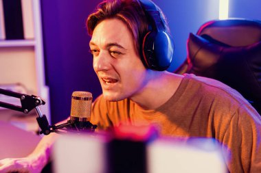 Oyun kanalı, online oyun oynayan akıllı flamalı oyun sunucusu, kulaklık takan, neon ışıklandırma odasındaki takım oyuncusuyla akıllı telefondan canlı yayında konuşan izleyiciler. Bireysel.