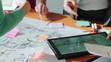 Mimarların el işaretleri tablet ekran planıyla toplantı masasının planına işaret ediyor. Akıllı mühendis takımının planlama ve renk paletlerine bakarken takım yazma fikrinin üst görüntüsü. Sempozyum.