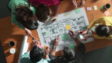 Beyin fırtınası yapmak için yapışkan notlar kullanarak inşaat mühendisi yazma ve planlamasının en üst görüntüsü. Yukarıdan aşağıya iş adamlarının proje planları ve ekipmanlarla masaya not almalarını gösteren bir görüntü. Sempozyum.