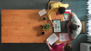 Renk paletinden renk seçmek için birlikte çalışan iş adamlarının üst düzey hava görüşü. İşadamı logo grafiğine bakarken pazarlama ekibine tablet kullanarak yönetici fikri sundu. Sempozyum.