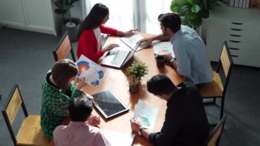 Proje yöneticisinin üst görünümü toplantıda yatırımcılara mali grafik sunuyor. Profesyonel pazarlama ekibi dizüstü bilgisayardan finansal istatistiklere bakarken finansal fikir üretiyor. Cemaat.