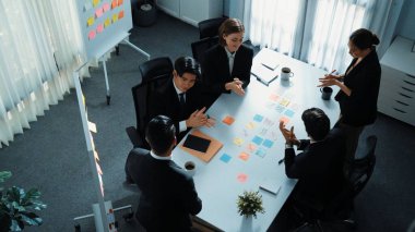 Akıllı yönetici finansal grafiğinin üst görüntüsünden çeşitli takımlara geçerken, bir grup çok kültürlü iş adamı toplantıda hisse yatırım grafiği kullanarak pazarlama stratejisi planlıyorlar. Müdürlük.