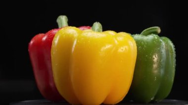 Bu çarpıcı makrografide kırmızı ve sarı dolmalık biberler siyah arka planda. Her yakın çekim zengin renkleri, karmaşık dokuları ve dolmalık biberlerin büyüleyici detaylarını yakalar. Geliştirilebilir.