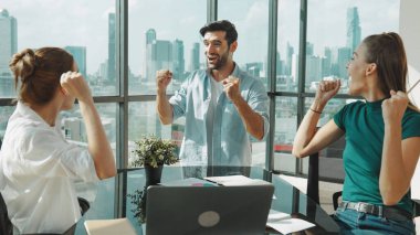 Profesyonel iş ekibi başarılarını kutlarken dizüstü bilgisayar kullanarak iyi haberler alıyor. Proje yöneticisi çak bir beşlik ve modern ofisteki meslektaşınla el çırp. İzleme