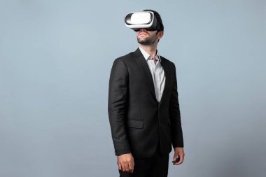 VR gözlüklü yetenekli bir proje yöneticisi ayakta dikilip etrafa bakıyor. Beyaz iş adamı takım elbise giyerken metaevren ve sanal gerçeklik dünyasına bağlanıyor. Yenilik teknolojisi. Sapma.