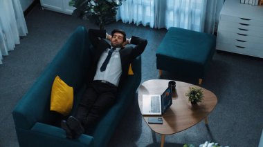 Stres atmak için kanepede yatarken dizüstü bilgisayarda çalışan yetenekli iş adamlarının üst görüntüsü. Stresli Kafkasyalı işçiler, kanepede uyurken iş planı ya da pazarlama stratejisini düşünüyorlar. Müdürlük.