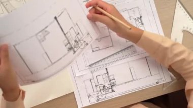 Ölçüm aracı ve kalem kullanan akıllı mimar ya da mühendisin videosu mimari ofisteki inşaat doğruluğu için bir el taslağı ayrıntılı taslağını karşılaştırıyor. Eline odaklan. - Yakın çekim. Tanımlama.