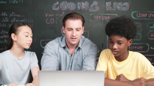 白种人老师一边教工程代码一边看笔记本电脑 在快乐的高中学生学习和学习编程系统中使用笔记本电脑的智能教师 — 图库视频影像