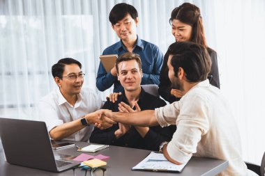 Çeşitli ofis çalışanları stratejik iş pazarlama toplantısı üzerine anlaşma yaptıktan sonra el sıkışıyor. Takım çalışması ve olumlu tutum verimli ve destekleyici bir iş yeri yaratır. Tedbirli