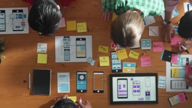 Mobil telefon arayüzü için Ux Ui tasarımı planlarken iş adamlarının yapışkan notlar üzerine yazı yazma fikrine tepeden aşağı bakış açısı. Bir grup yaratıcı tasarımcı kablo prototip tasarımı üzerinde çalışıyor. Cemaat.