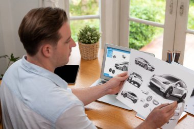 Araba tasarım mühendisi otomobil işi için otomobil prototipini ev ofisinde analiz ediyor. Otomotiv mühendisliği tasarımcısı dikkatle analiz ederek, dizüstü bilgisayarla araba tasarımında kusurlar ve iyileştirmeler buluyor.