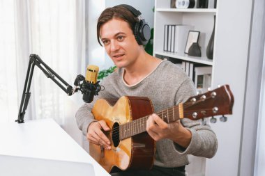 Gülümseyen yüzlü akıllı şarkıcının sunucu kanalı, şarkı söylerken gitar çalmak, sosyal medya kanalında yayın yapmak, modern stüdyo kaydında video kaydedici olarak kulaklık takmak. Bireysel.