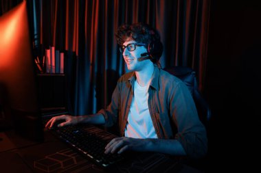 PC dövüş oyununda Esport 'ta oyun çubuğuyla oynayan gülümseyen genç oyun flaması takımı, kırmızı neon ışıklı modern odada gelecek için strateji planlamasında rakiplerini kazanmaya çalışıyor. Toplayıcı.