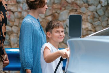 Elektrikli araçla aile seyahati, güzel bir aile arabası yeşil ve temiz enerjili. Kaya gibi sağlam bir arka plan ve sürdürülebilir çevre için çevre dostu araba yolculuğu. Kalıcı