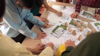 Mimari belge, ölçüm aracı ve ahşap blokların modern ofiste etrafa saçıldığı bir masa üzerinde yapı inşaatı ile ilgili mimar ve güvenlik mühendisi tartışması. Tanımlama.