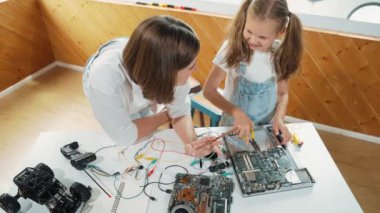 Kafkas öğretmeninin öğrencilere elektronik kurulun bir parçasını öğretmesi. Uzman kız dijital elektrikli aletleri öğreniyor ve cips ve kablolarla ana kartı tamir ediyor. Etkinlik.