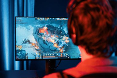 Savaş arenasında çoklu oyunlar takımıyla Moba 'da savaşan genç oyun flamasının sunucu kanalı, neon dijital ışık modern odasındaki arka görüntü ile bilgisayar monitöründe kulaklık takıyor. Toplayıcı.