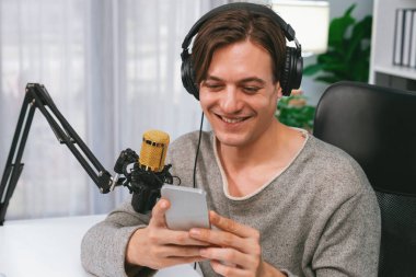 Akıllı yayıncının sunucu kanalı canlı sosyal medya yayını ile akıllı telefon kullanarak dinleyiciyle sohbet ediyor, kulaklık takarak modern ev stüdyosunda video kaydediyor. Bireysel.