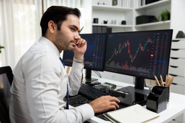 Akıllı tüccar işadamı, modern merkez ofisindeki araştırma pazarında en yüksek kârlı finansal teknolojiye yatırım yaparak bilgisayar üzerinde iki dinamik borsa yatırım ekranını analiz ediyor. Tahmin et..