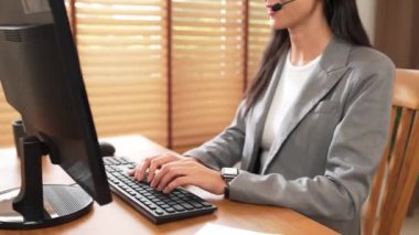 Kadın çağrı merkezi operatörü ya da müşteri hizmetleri çalışanı, müşteriye yardım etmek için kulaklıkla konuşurken çalışma alanı üzerinde çalışıyor. Profesyonel modern iş hizmeti. Blithe