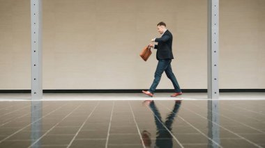 İş adamının iş yerine giderken tren istasyonuna yürürken saatine bakması. Akıllı Kafkas yöneticisi modern şehir boyunca yürümek ve buluşmak için zamanı kontrol ediyor. Urbane.