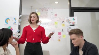 Yetenekli genç ve güzel iş kadını, yaratıcı iş toplantısında yakışıklı yönetici dinlerken zihin haritalama ve istatistiksel grafik kullanarak pazarlama fikrini kendine güvenle sunuyor. Tertemiz..