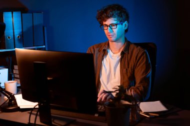 Genç işadamı, Neon Light Modern Ofis 'te yaratıcı bir başlangıç projesi için bilgisayara odaklanıyor. Düşünüyorum da, pazarlama ağı yaratıcıdan pazar kanalı tasarım konseptine çevrimiçi planlama. Toplayıcı.