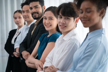 Mutlu ve gülümseyen çok ırklı ofis çalışanı, sinerjiyi ve ticari başarı için işbirliğini destekleyen bir kuyrukta el ele tutuşuyor. Modern işyerinde çeşitli profesyonel ofis çalışanları arasında bağ var. Uyum